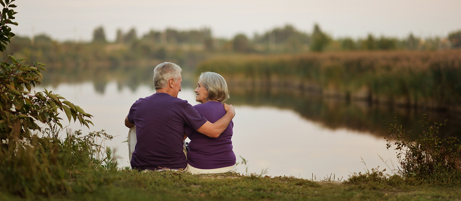 elderly couple sitting in front of lake