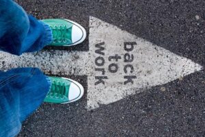 Image of a person's feet on asphalt with an arrow reading Back to Work