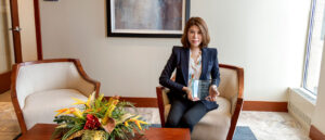 Woman sitting in an office holding an award on PSA Insurance & Financial Services' website