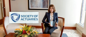 Society Of Actuaries logo over an image of a woman sitting in a chair holding an award on PSA Insurance & Financial Services' website