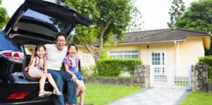 Image of a father and two daughters sitting in a car in front of a house smiling on PSA Insurance & Financial Services' website