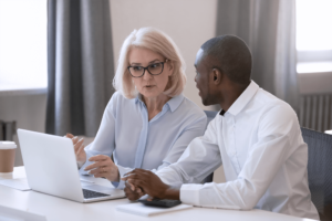 Two people sitting at a computer and talking on PSA Financial's website