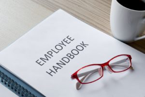 Image of a binder reading "Employee Handbook" with glasses set on it on PSA Financial's website