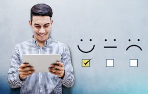 Image of a person smiling and holding an ipad with a checkmark under a smiling graphic and an empty box under a frowning one on PSA Financial's website