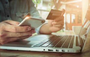 A person holding a phone and a credit card on PSA Financial's website