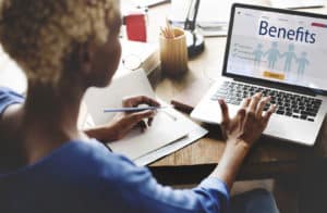 A person using a laptop and writing on paper on PSA Financial's website