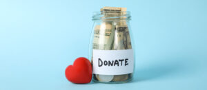 Image of jar with cash in it labeled "Donate" and a red heart on PSA Financial's website