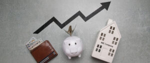 Image of a wallet, piggy bank and miniature of a business building under an arrow