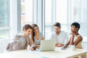 Image of a group of happy employees sitting at a desk looking at a laptop