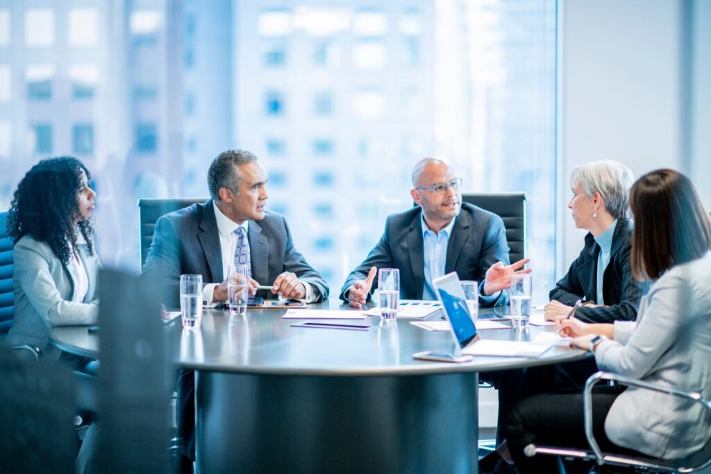 Image of a group of business people sitting at a desk in an office