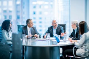 Image of a group of business people sitting at a desk in an office