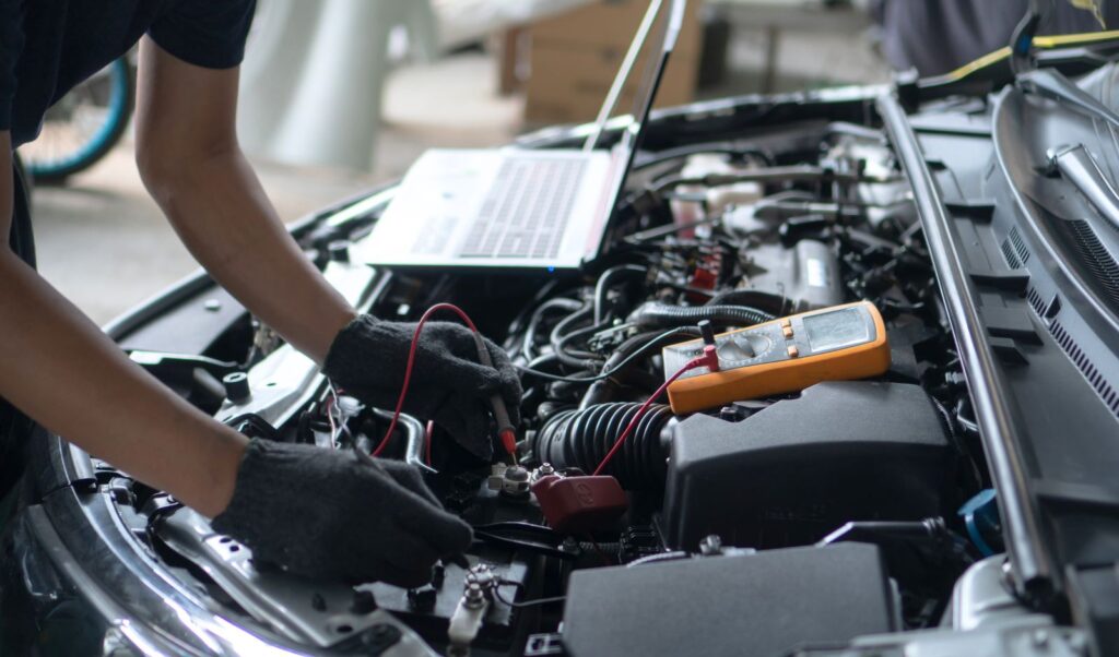 Image of a person working under the hood of a car