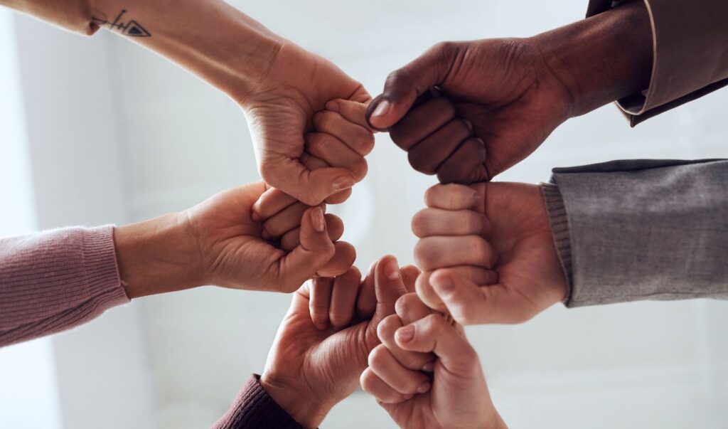 Image of six people fist-bumping