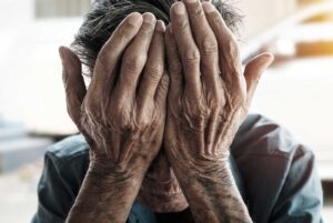 Image of an older person with their head in their hands