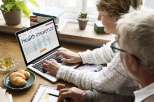 Image of two people looking at a laptop screen reading "health insurance"